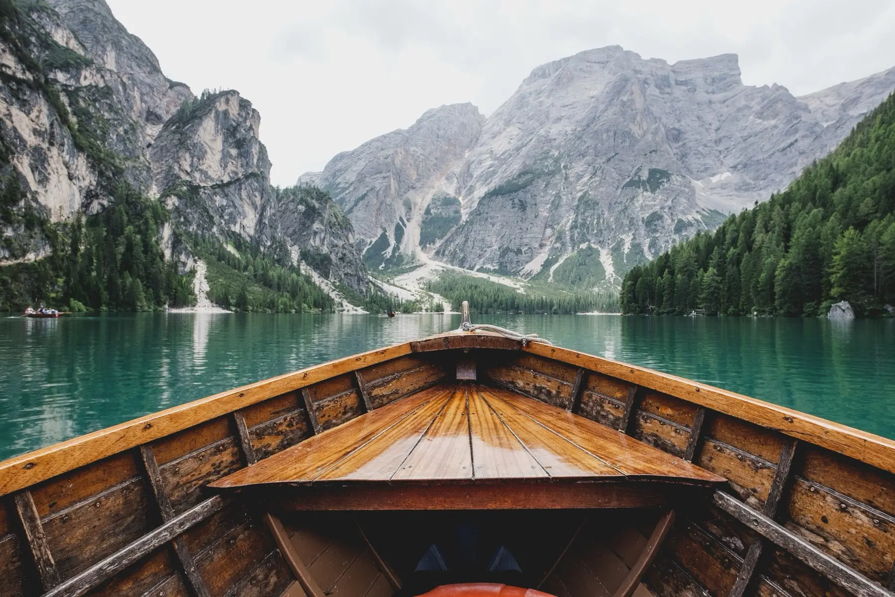 The bow of a wooden rowing boat on the turquoise water of Lago di Braies