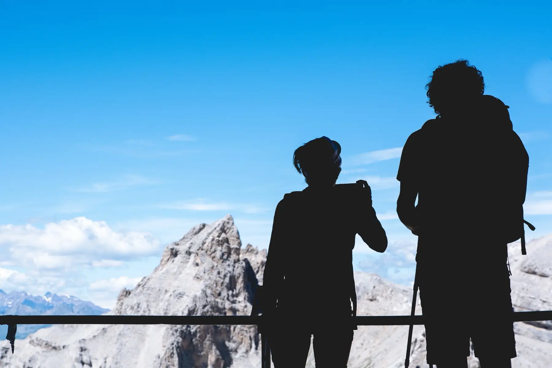 Two walkers silhouetted against a snowy limestone peak