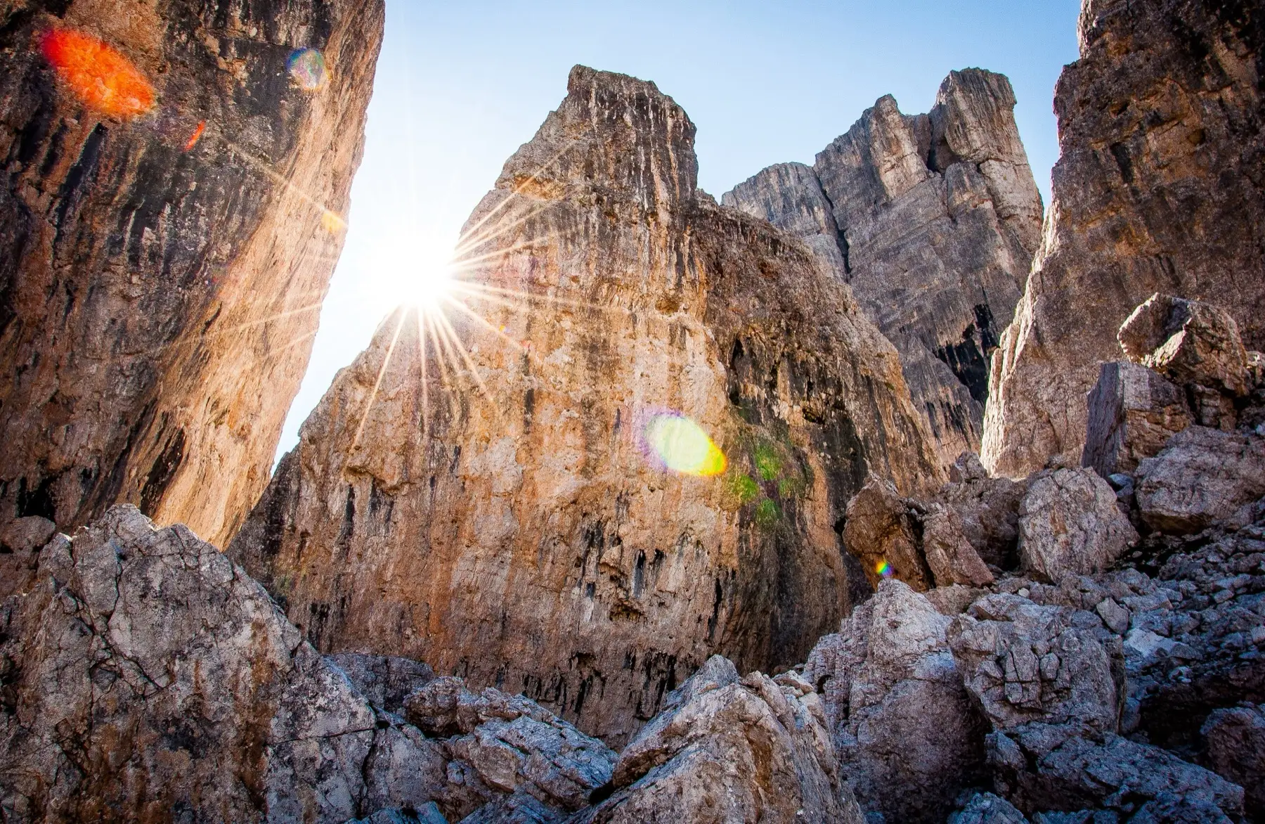 Sun breaking between tall limestone towers above a boulder field