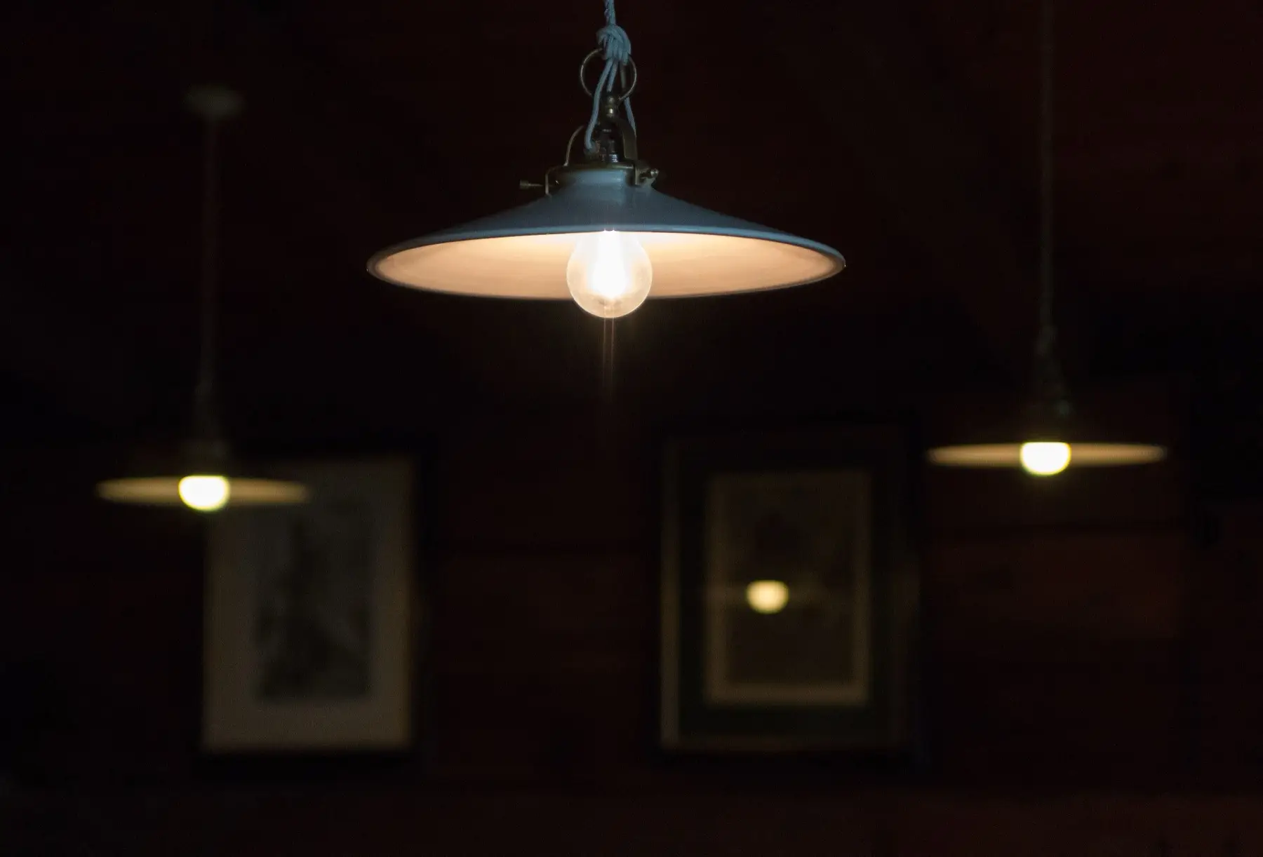 Lamps glowing over a dark wood-paneled hut dining room
