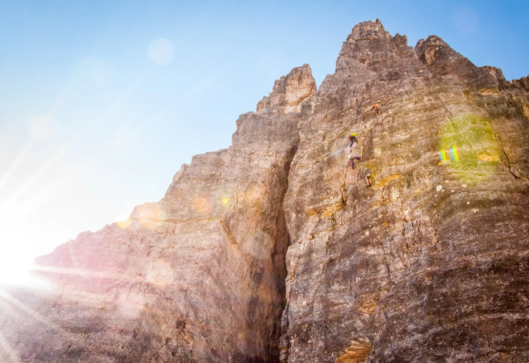 Climbers below a tall limestone wall above Cortina