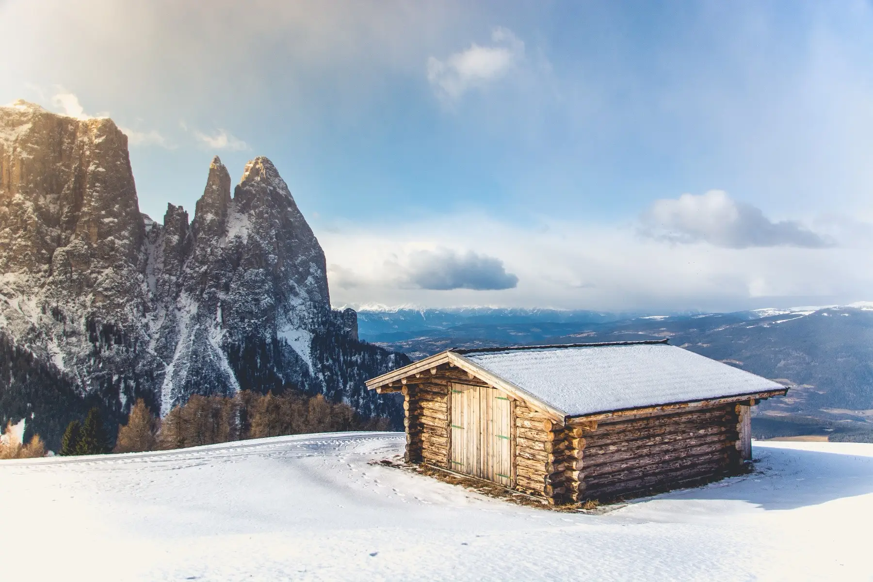 A wooden hut in deep snow beneath the Sassolungo